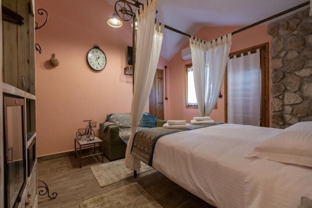 A bedroom with a bed, a bedside table, a clock on the wall, and a window with curtains.