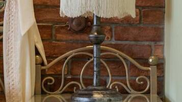 A lamp on a wooden nightstand with a decorative drawer front, set against a brick wall.