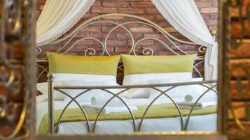 A bed with a metal frame, draped white curtains, and a yellow pillow.