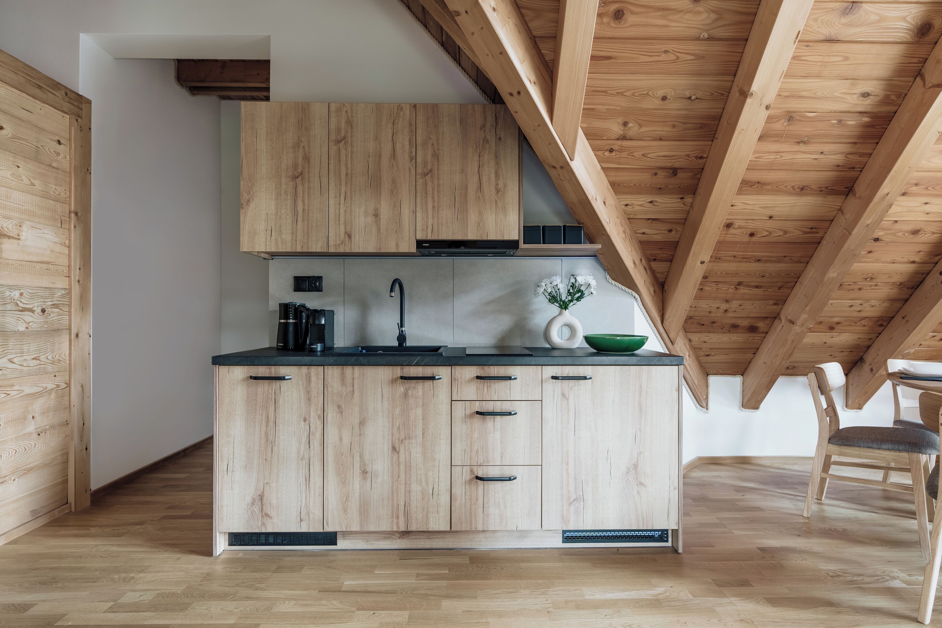 Una cocina moderna con armarios de madera, encimera negra y techo de madera.