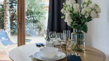A dining table set with a white bowl, plates, cutlery, and a vase of white flowers.