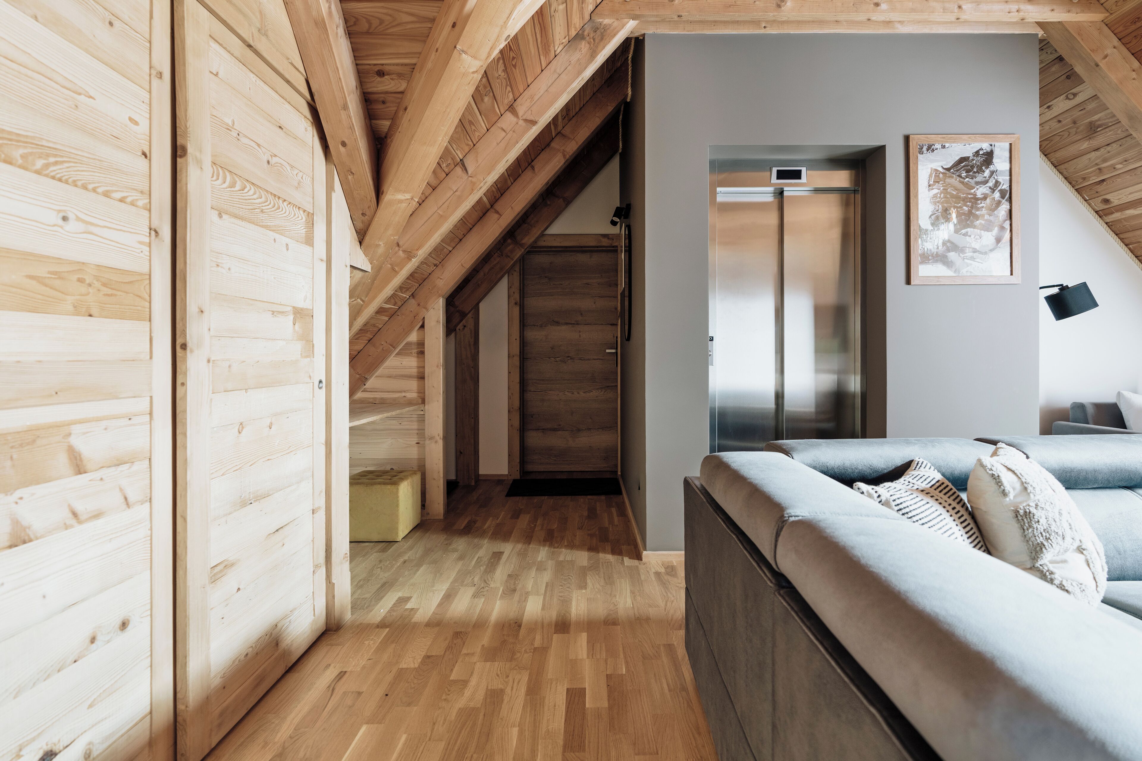 A modern interior with wooden beams, a sofa, and a framed picture on the wall.