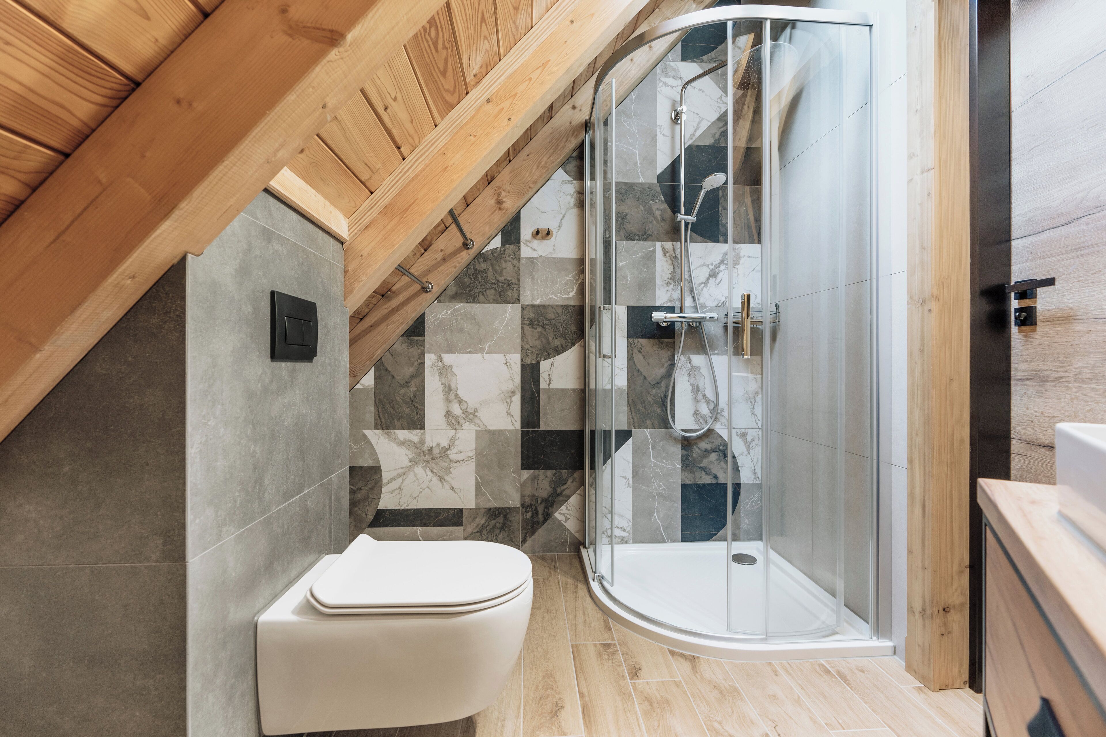A modern bathroom with a glass shower enclosure, a white toilet, and a tiled floor.