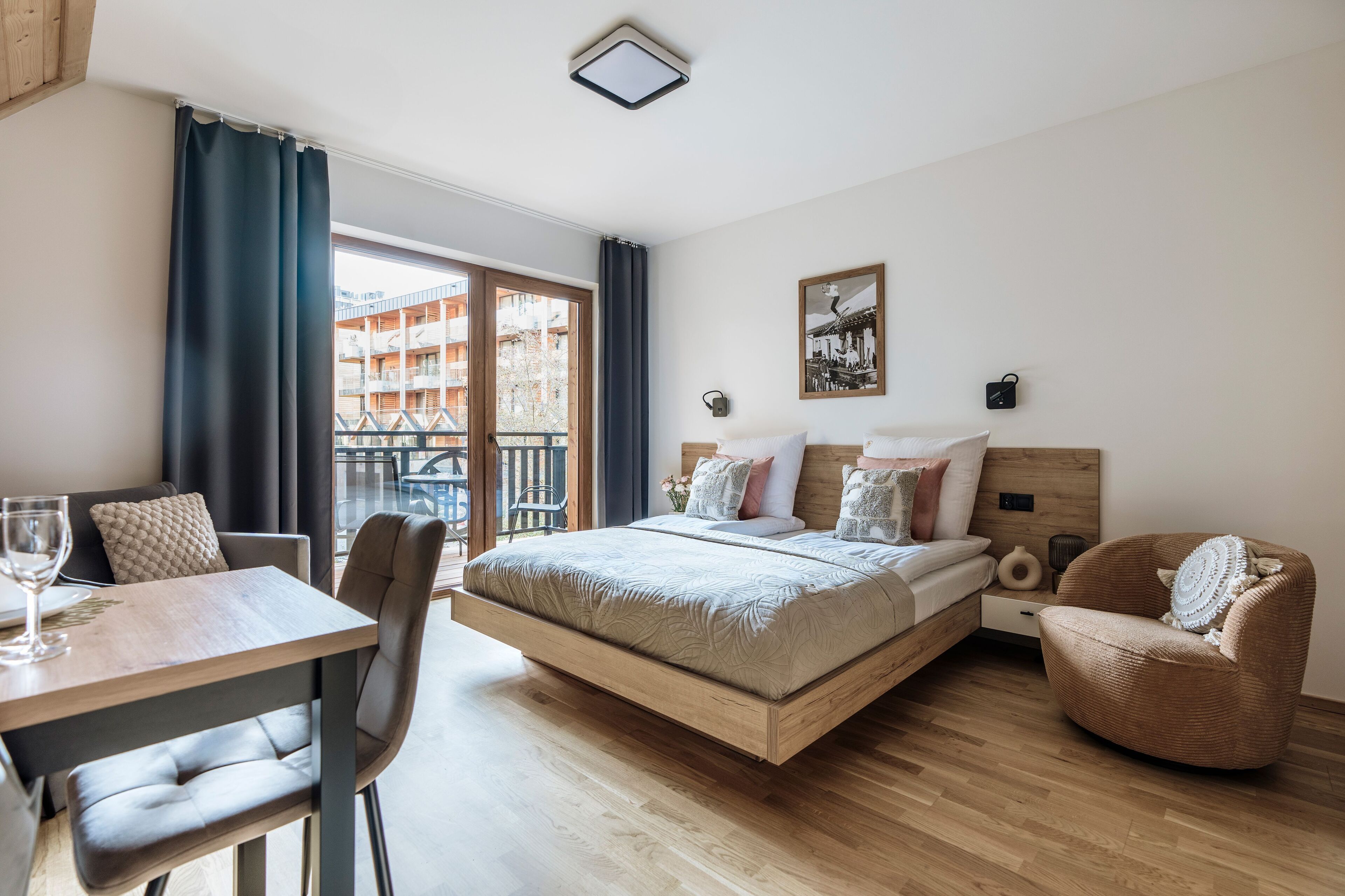 A modern bedroom with a wooden bed, a dining table, and a chair.