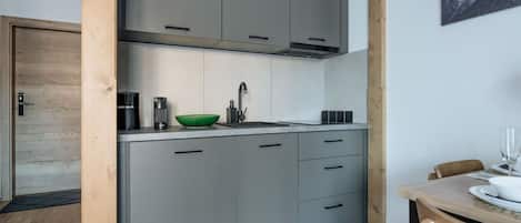A modern kitchen with grey cabinets, a green bowl, and a coffee maker.