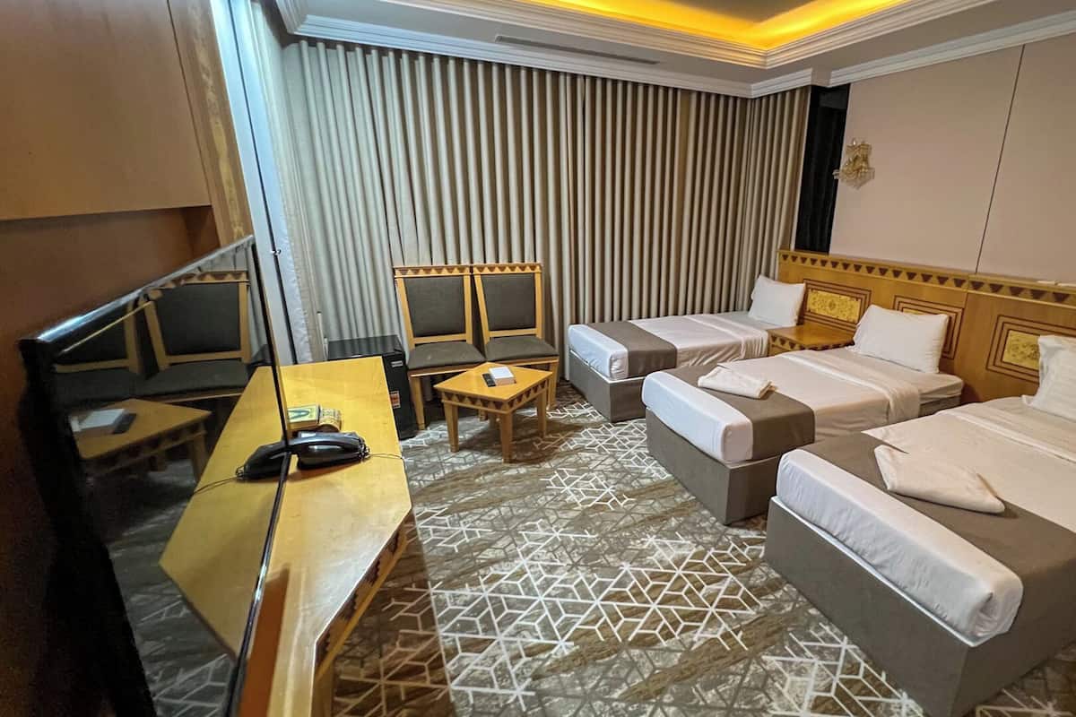 Une chambre d’hôtel avec deux lits, un bureau, une chaise et une petite table.