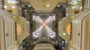 A symmetrical, ornate corridor with a central circular light fixture, flanked by mirrored walls and geometric patterns. - Rahaf Almashaer Hotel (Makkah)