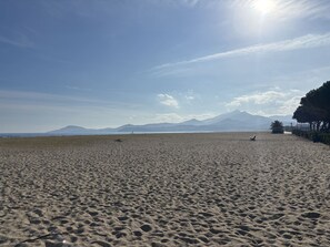 A wide sandy beach with footprints, a clear sky, and distant mountains. - Argelès-sur-Mer Ground Floor 1-BR with Terrace & Parking by Beach (Argelès-sur-Mer)