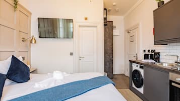 Une chambre d’hôtel équipée d’un lit, d’une machine à laver, d’un lavabo et d’un téléviseur fixé au mur.