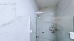 A glass-enclosed shower with a handheld showerhead, a glass door, and a marble-tiled wall. - Jardim dos Corais - Praia de Tamandare (Tamandaré)