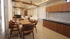 A modern kitchen with wooden cabinets, a marble countertop, and a dining area with a wooden table and chairs. - A 26 Hilltop Heaven Resort (Udaipur)