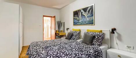 Ein Schlafzimmer mit Bett, Nachttisch, Lampe und einem Bild an der Wand.