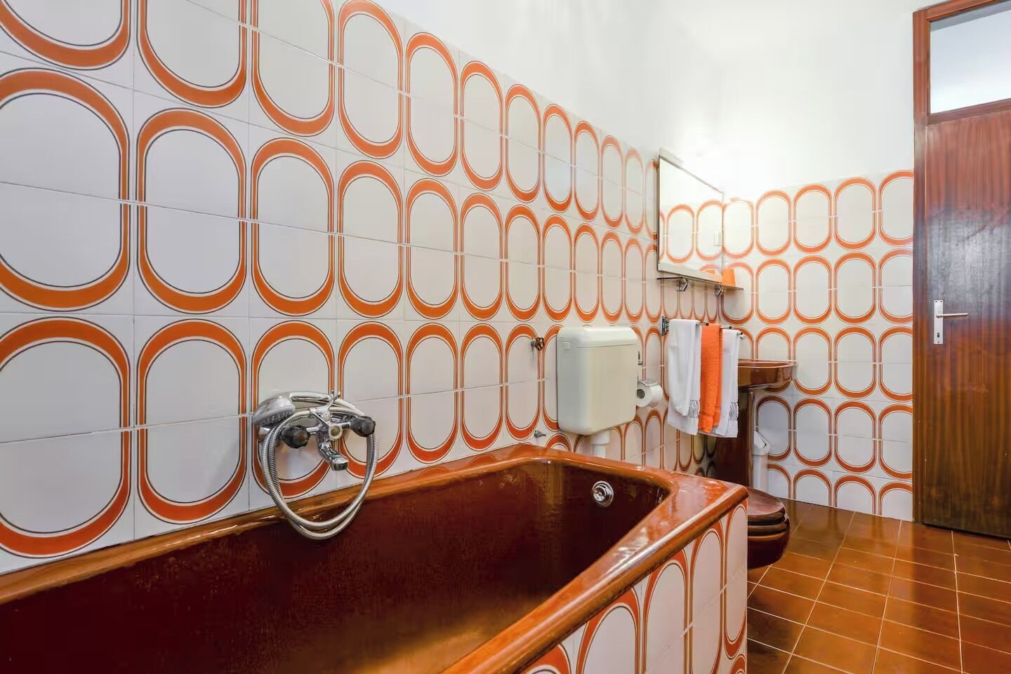 A bathroom with a bathtub, a hand shower, and a toilet.