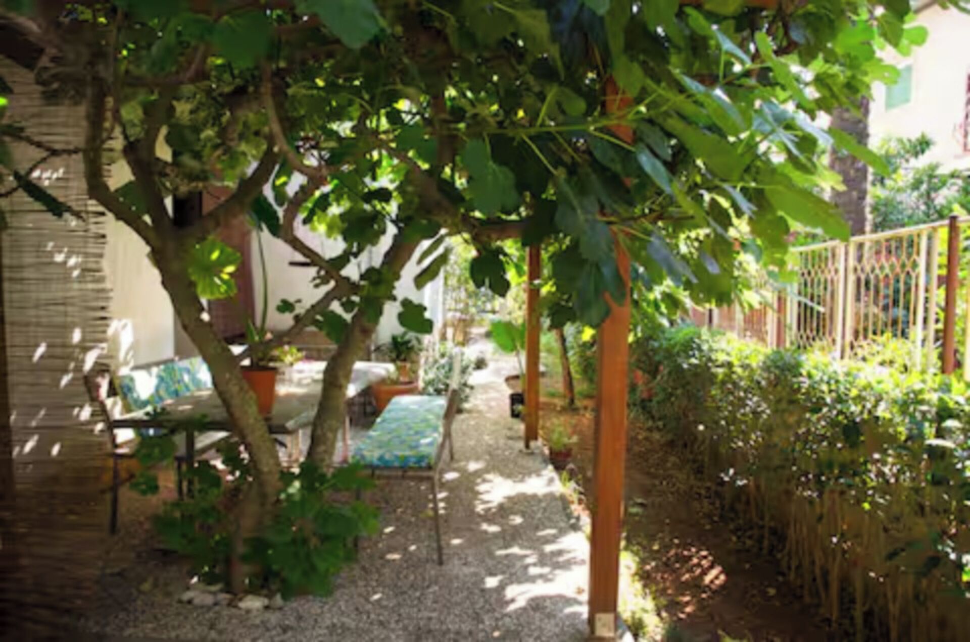 Ein Garten mit einer Pergola, einer Bank und einem Weg.