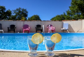 A swimming pool with two glasses of water and lemon slices, surrounded by chairs and a clear sky. - Gîte Les Racines de Lili with Private Pool, Terrace, and Wi-Fi in Cieurac (Cieurac)
