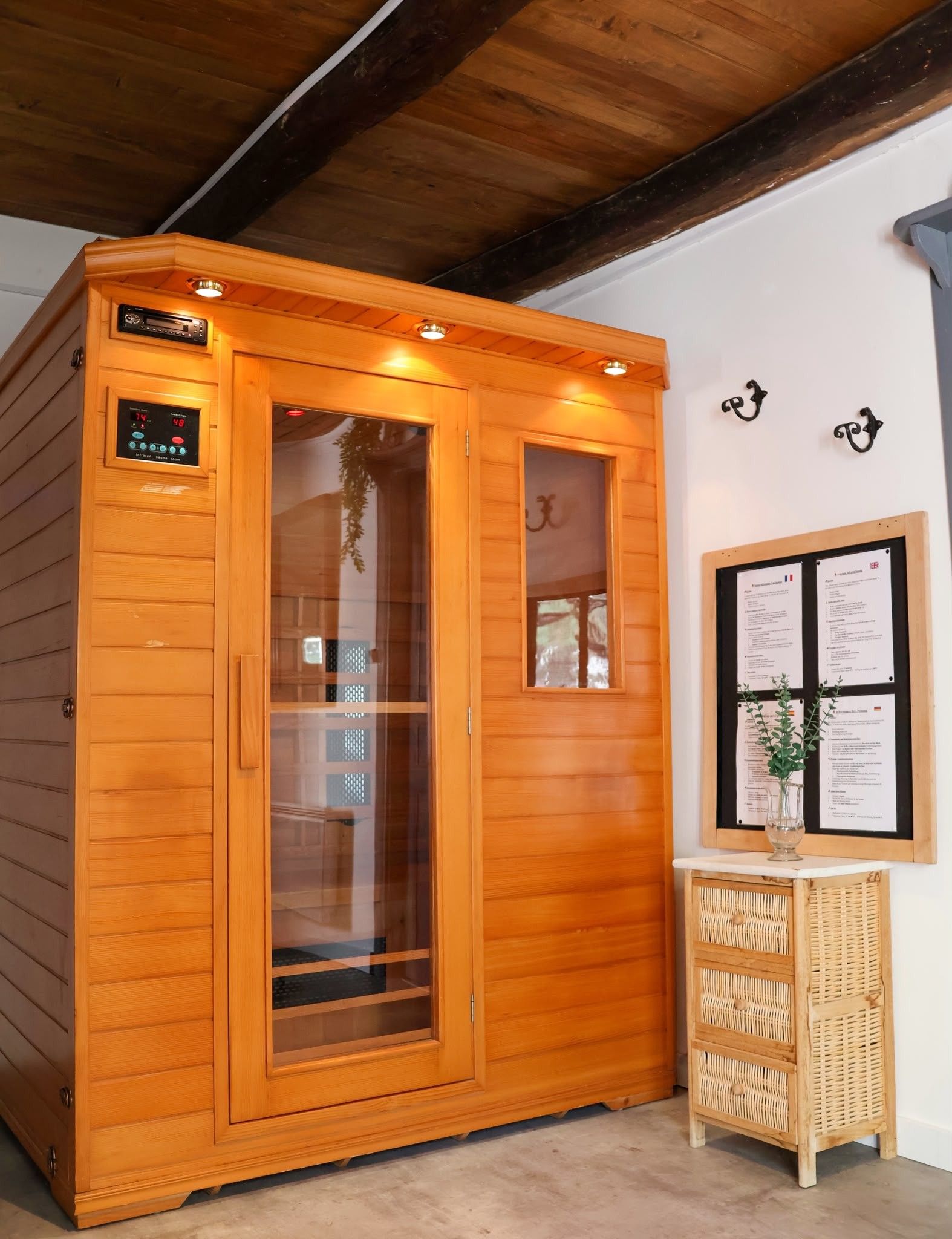 Een sauna met een digita bedieningspaneel, een glazen deur en een houten interieur.