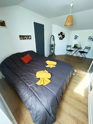 Quarto com uma cama grande, um espelho, uma pequena mesa e uma cadeira.