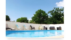 Une piscine avec des chaises longues et un ciel dégagé.