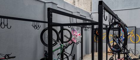 A bike rack with multiple bicycles parked against a grey wall.