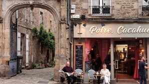 An outdoor café with stone architecture, outdoor seating, and a visible menu board. - "Le Clos Lesage", charming house with garden, at the foot of the chateau (Dinan)