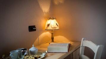 Un coin accueillant avec une table préparée pour le petit-déjeuner, comprenant un plateau avec du pain, un livre et une tasse. Une lampe diffuse une lumière chaleureuse.