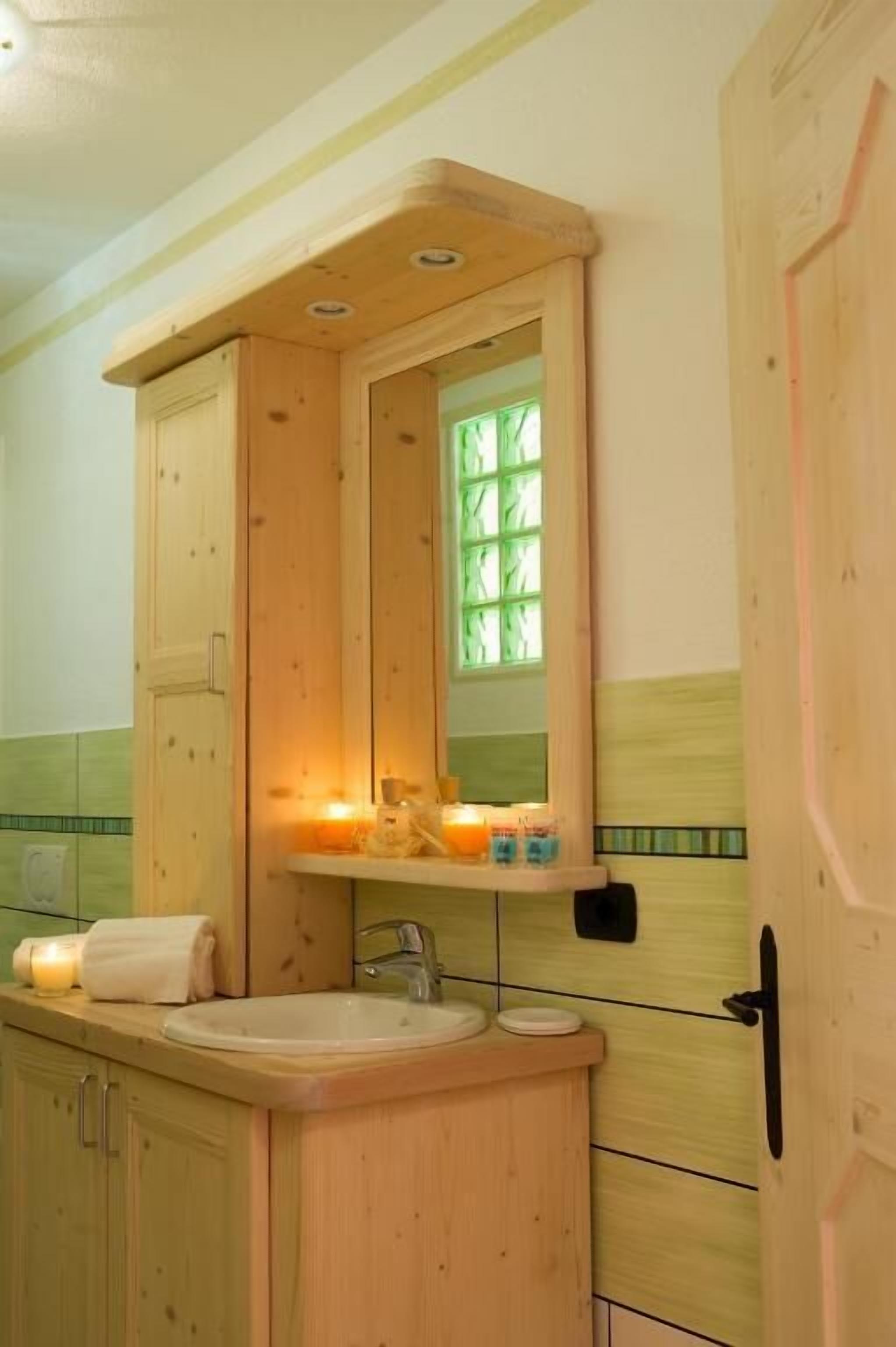 A wooden bathroom with a sink, mirror, and candles.