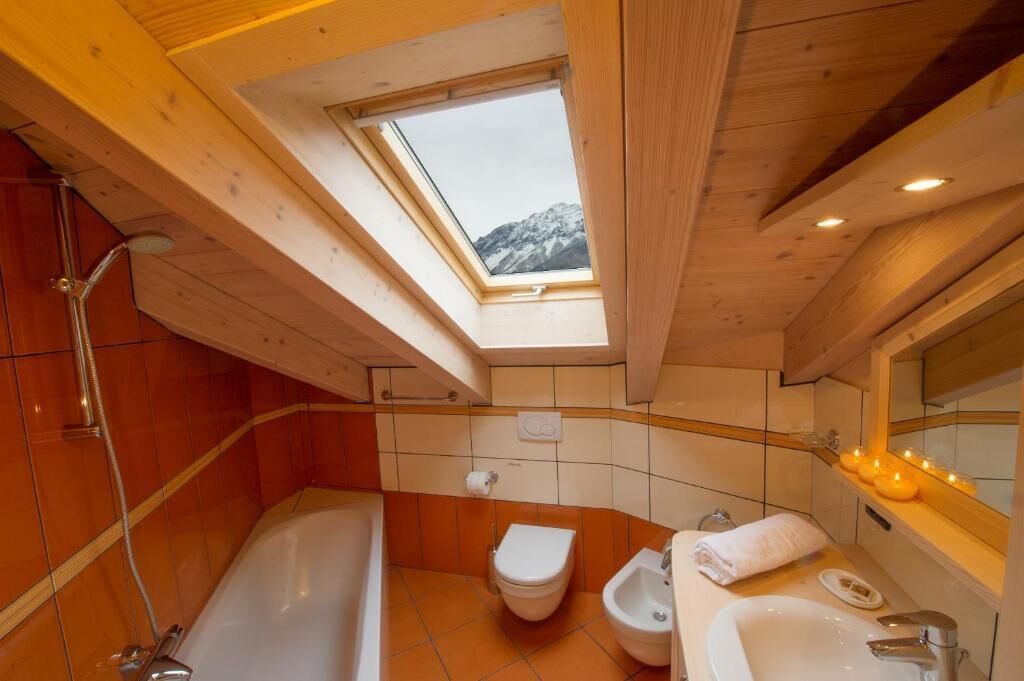 Ein Badezimmer mit Dachfenster, einer Badewanne, einer Toilette, einem Bidet und einem Waschbecken.