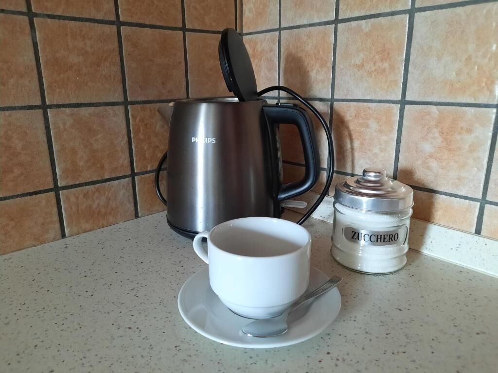 Un comptoir de cuisine avec une machine à café, une tasse de café et un récipient à sucre.
