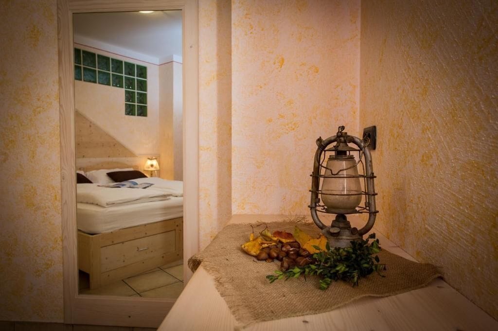 Un dormitorio con una cama, una mesita de noche con lámpara y un radiador fijado a la pared.