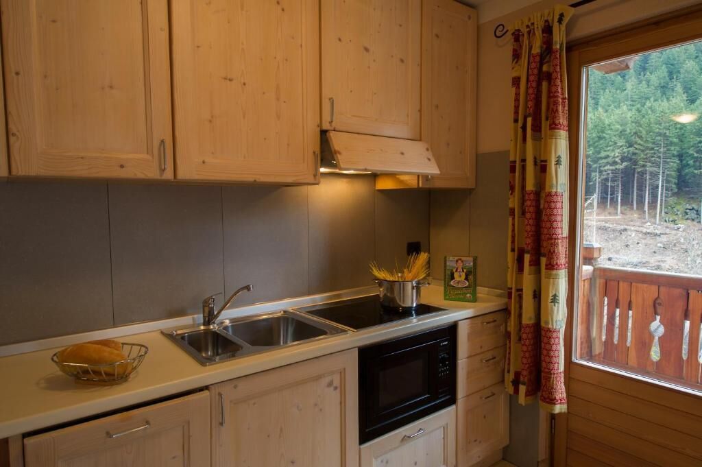 Una cocina con armarios de madera, un fregadero, una estufa y una ventana con vistas a árboles.