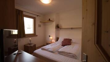 Ein Schlafzimmer mit Bett, Nachttisch, Lampe und Spiegel.