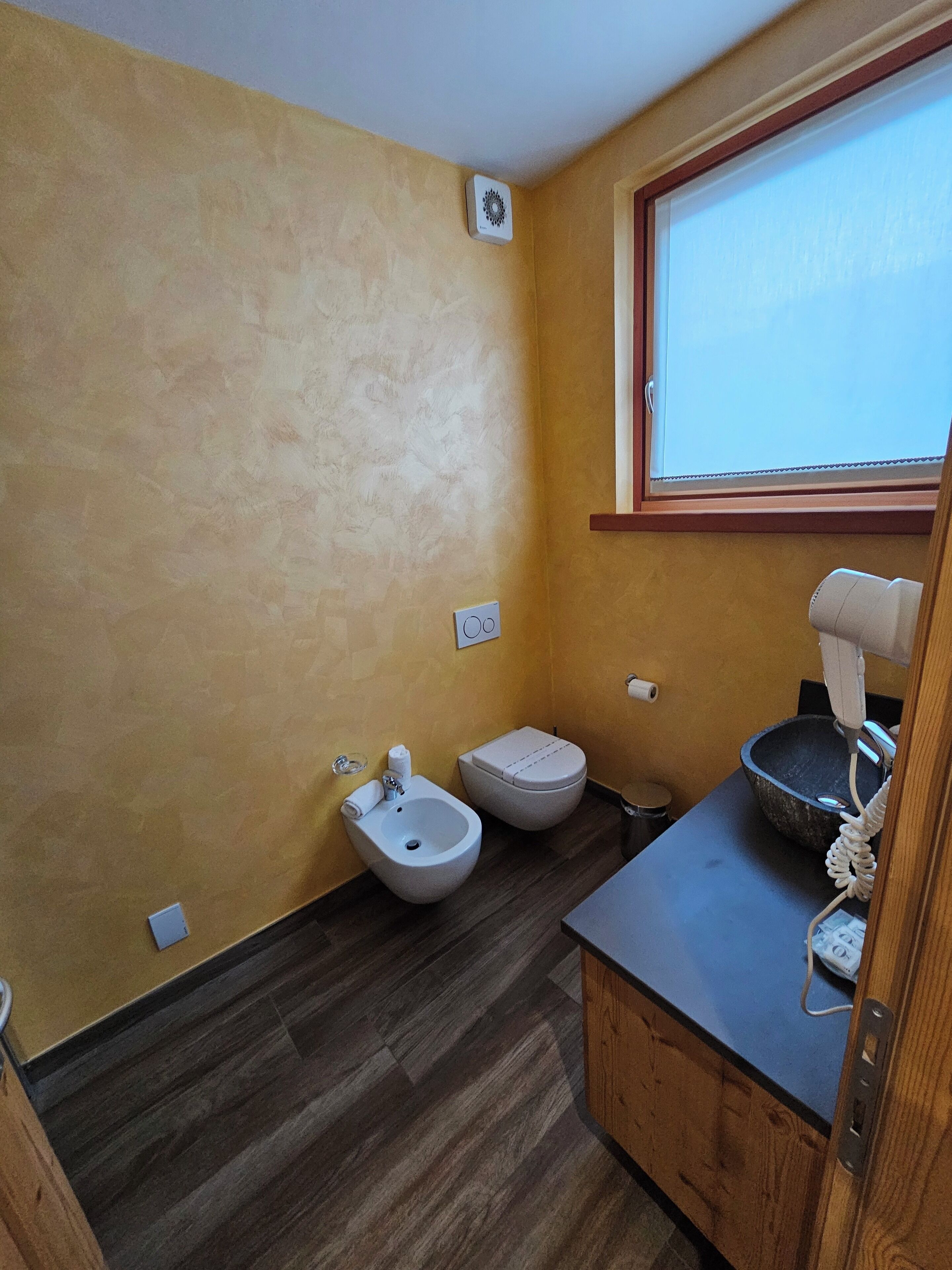 A small bathroom with a bidet, toilet, and sink.