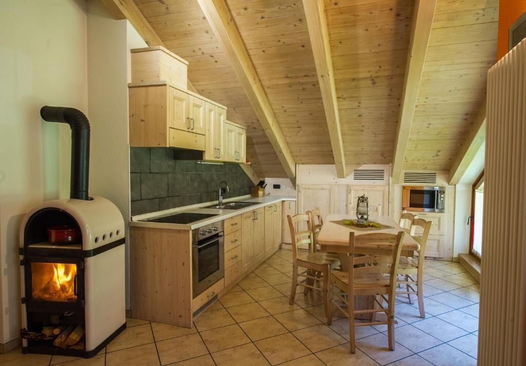Eine gemütliche Küche mit Kaminofen, Holzschränken und einem Essbereich mit Stühlen.