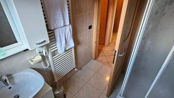 A bathroom with a sink, mirror, towel rack, and shower.