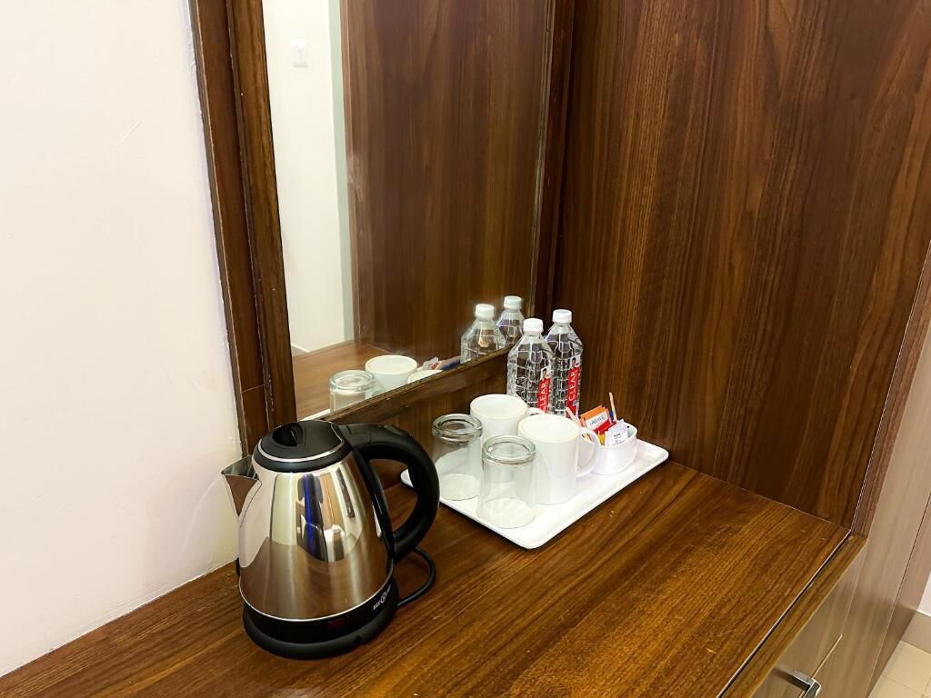 A wooden counter with a kettle, cups, and bottles.