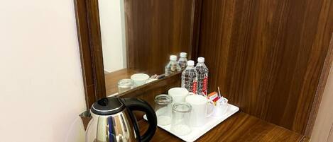 A wooden counter with a kettle, cups, and bottles.