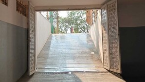 Un couloir étroit, doté d’un plancher en bois, mène à une porte ornée de motifs géométriques.