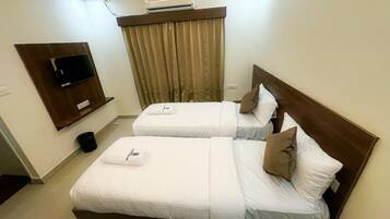 Habitación de hotel con dos camas, un televisor montado en la pared y una ventana con cortinas.