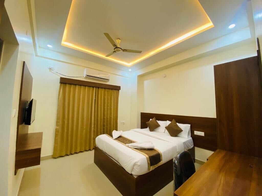Habitación de hotel con cama, escritorio, ventilador de techo y aire acondicionado.