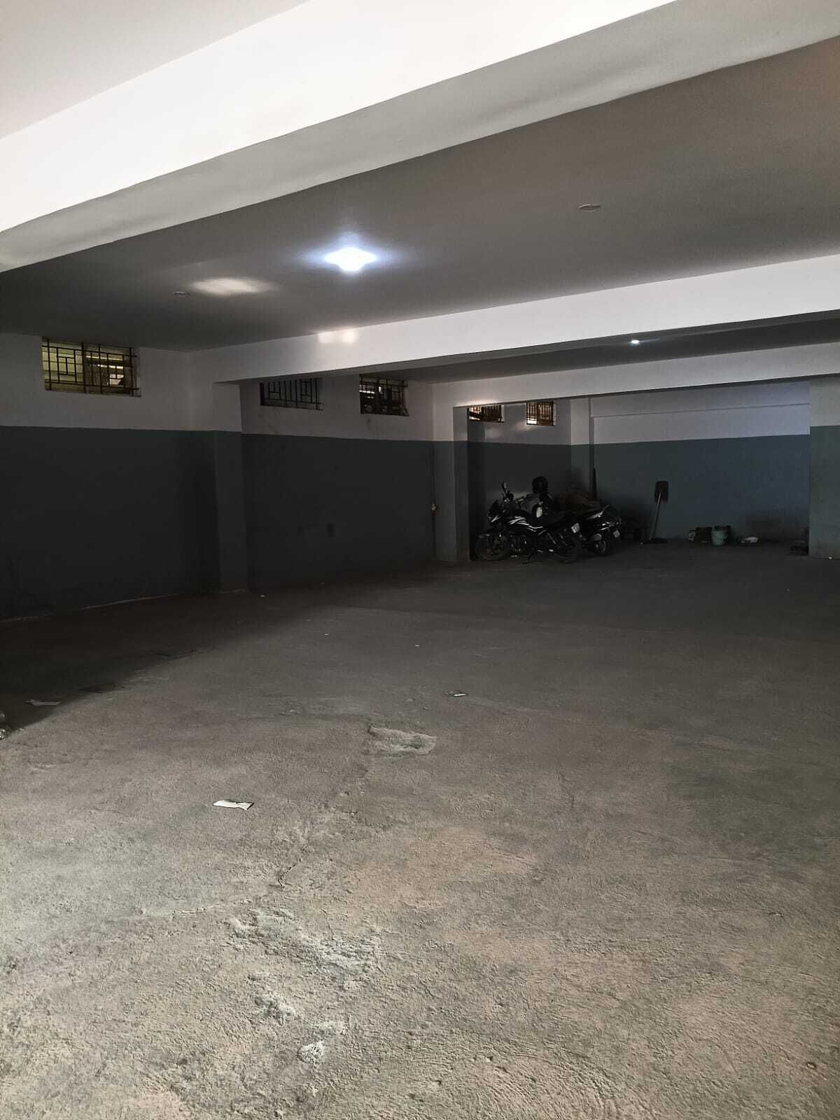 A spacious indoor parking area with concrete flooring and metal railings.