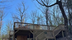 Eine Holzhütte mit einer überdachten Veranda und einer Treppe zu einer oberen Terrasse.
