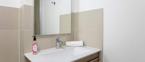 A bathroom with a white sink, a mirror, a towel, and a bottle of hand soap.