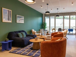 Ein moderner Lounge-Bereich mit einer Couch, Sesseln, einem Couchtisch und einem kleinen Beistelltisch.