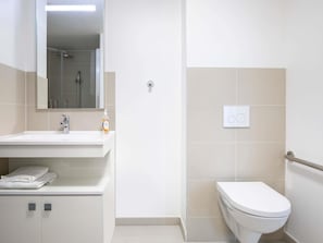 A modern bathroom with a white sink, mirror, and toilet. - Aparthotel Adagio Access Paris Nanterre (Nanterre)