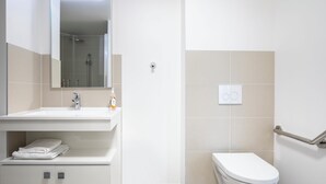 A bathroom with a sink, mirror, towel rack, toilet, and a shower area. - Aparthotel Adagio Access Paris Nanterre (Nanterre)