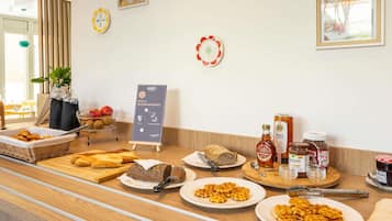 Ein Frühstücksbuffet mit Brot, Waffeln und Beilagen.