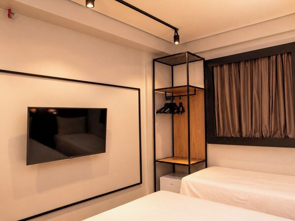 A modern hotel room with a bed, a TV mounted on the wall, a built-in wardrobe, and a window with curtains. - Ibis Araguaína (Araguaina)