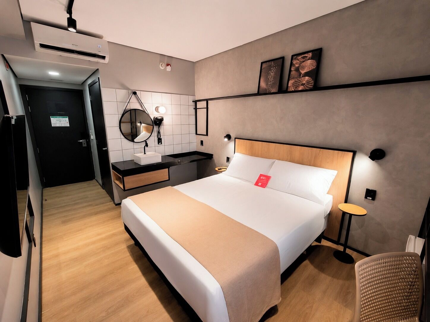 Ein Hotelzimmer mit Bett, Nachttisch, Spiegel und einem kleinen runden Tisch.