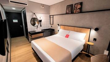 Ein Hotelzimmer mit Bett, Nachttisch, Spiegel und einem kleinen runden Tisch.