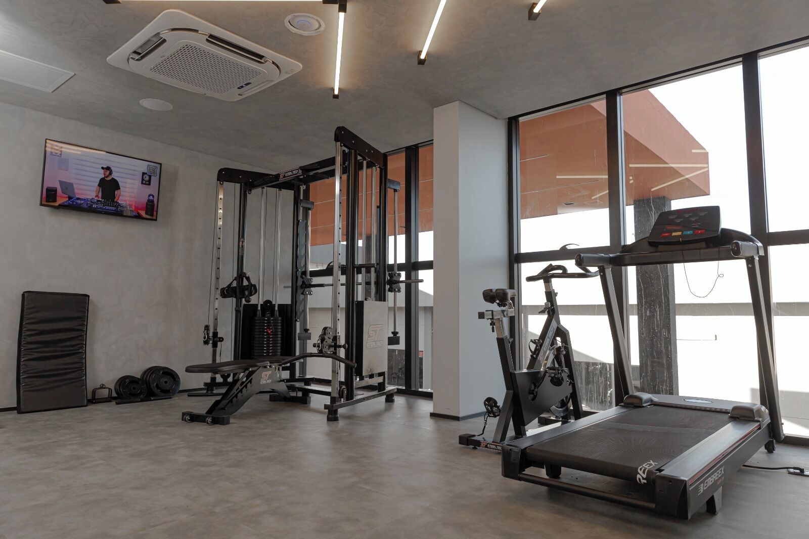 A gym with exercise equipment, a treadmill, and large windows.
